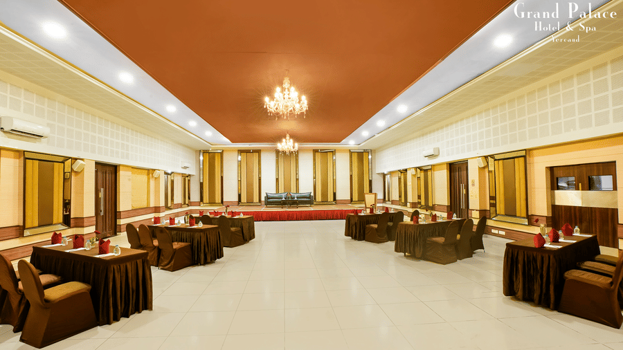 Large event space at Grand Palace, Yercaud arranged with sofa seating, open area, chandeliers, panoramic windows, and polished flooring for gatherings