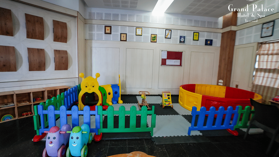 Kids play area at Grand Palace, Yercaud, with colourful indoor fencing, toys, seating and nursery wall art covering the indoor activity space.
