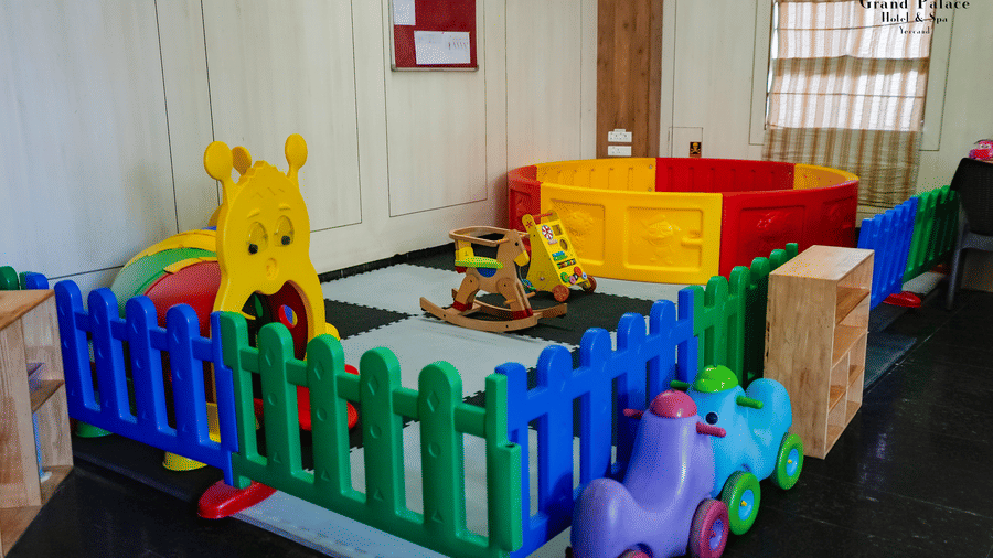 Soft play enclosure at Grand Palace, Yercaud, with bright plastic fencing, play vehicles, soft toys, seating, and indoor window creating safe play environment.