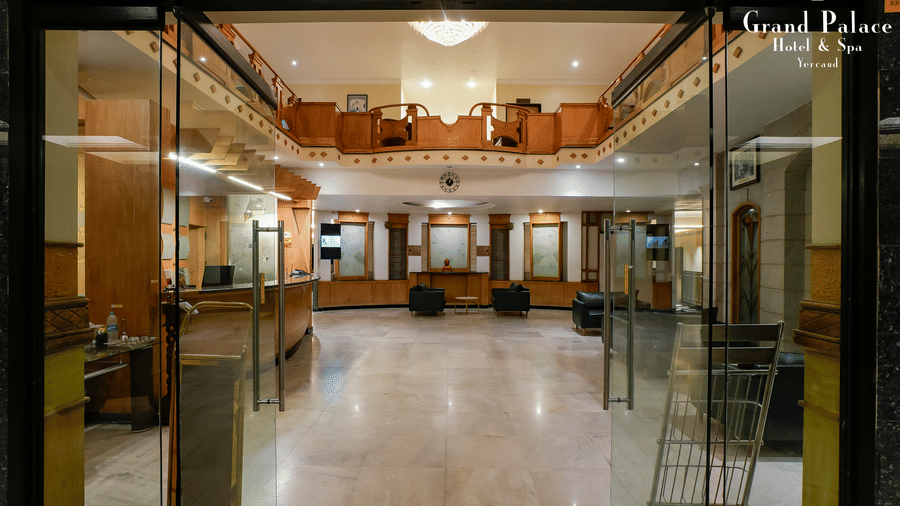 Glass-fronted entrance at Grand Palace, Yercaud, displaying lobby space, visible seating, and open interior design.