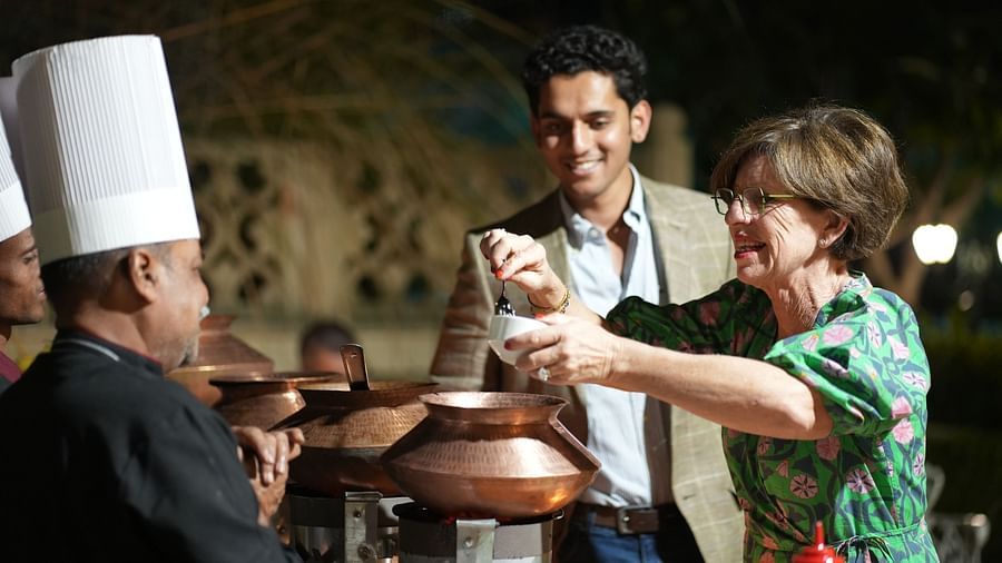 A waiter setting a table in an outdoor courtyard with traditional architecture - Khas Bagh, Jaipur.