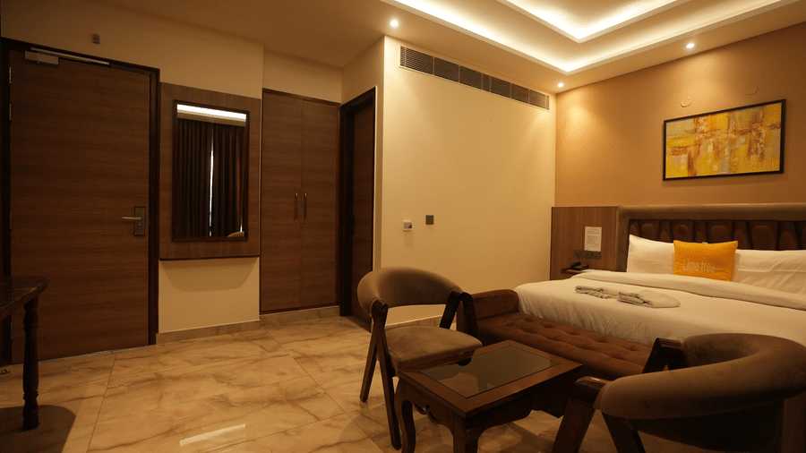 Entry view into a luxury hotel suite showing a tiled floor, dark wood panelling, and a seating area.