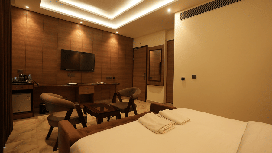 Wide-angle view of a premium hotel bedroom featuring integrated wooden furniture and subtle ceiling illumination.