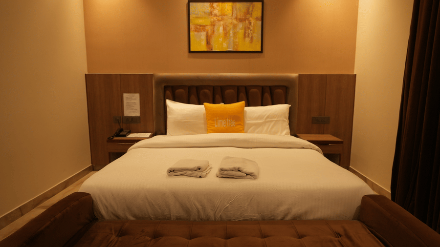 Premium hotel room setup highlighting a double bed paired with a brown plush upholstered footstool.