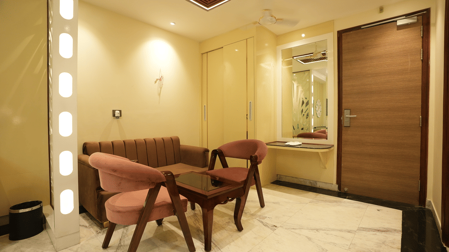 A cosy seating arrangement inside a hotel room with two pink upholstered armchairs and a small coffee table.
