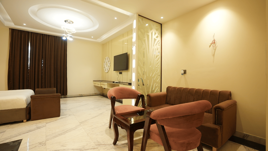 Open-plan hotel room layout displaying an integrated seating space with pink chairs next to the bed area.