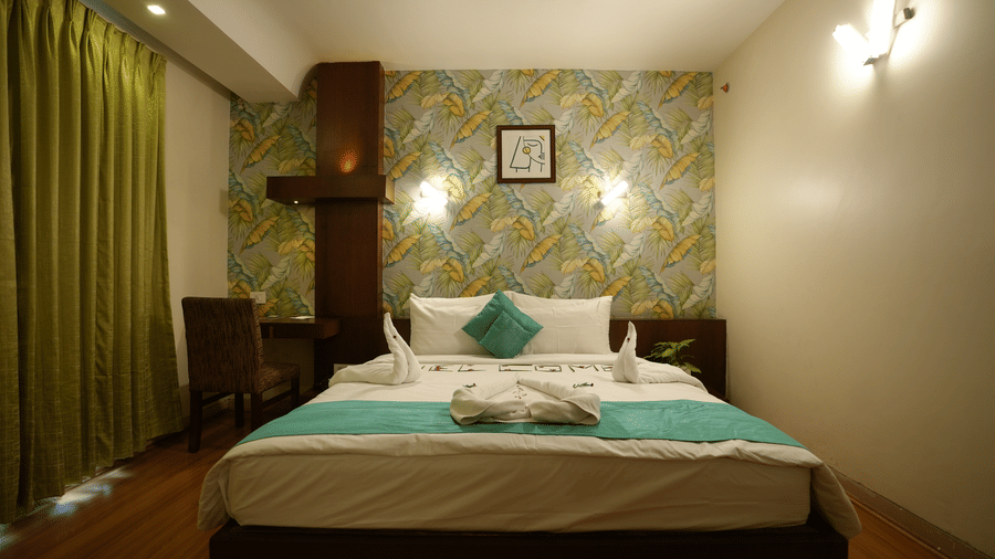 Comfortable double bedroom with patterned accent wall and soft lighting at Pipul Utkal Continental, Jharsuguda.