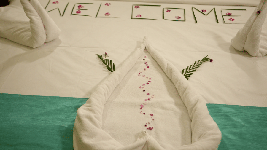 Welcome arrangement on a hotel bed with folded towels and floral decor at Pipul Utkal Continental, Jharsuguda.