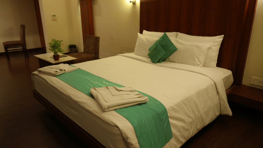 Spacious room with a bed and elegant wooden decor at Pipul Utkal Continental, Jharsuguda.