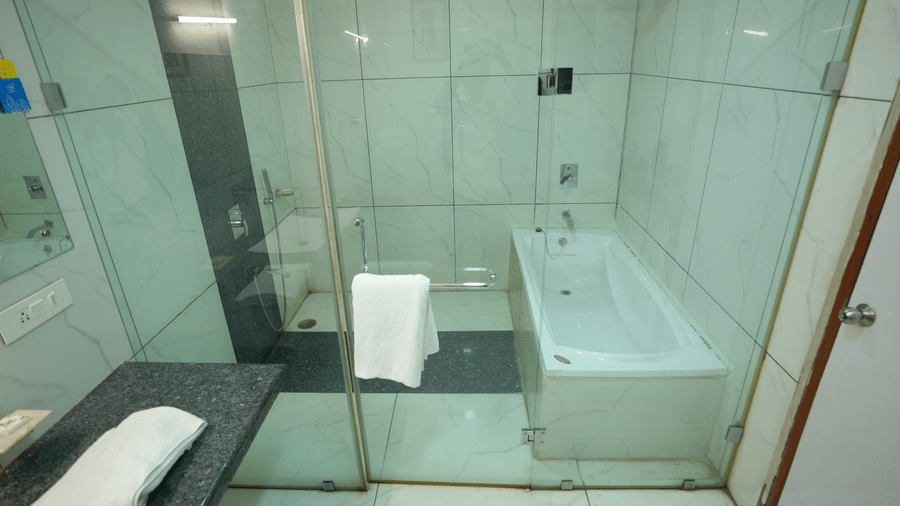 Modern bathroom with glass shower enclosure and clean white interiors at Pipul Utkal Continental, Jharsuguda.