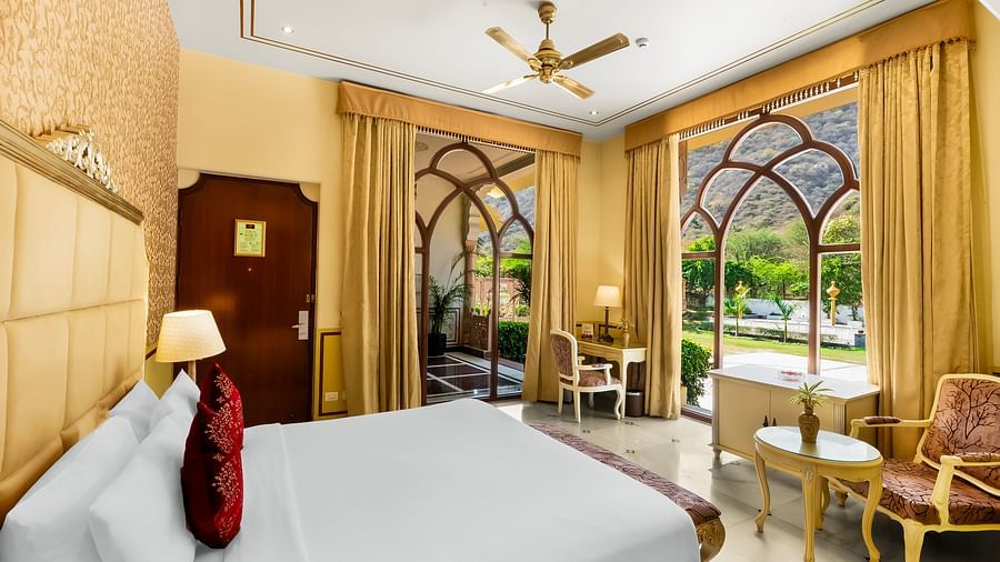 An overview of a room with a double bed and floor to ceiling windows in view - Rajasthali Resort & Spa, Jaipur.