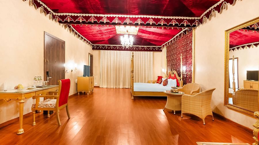 An overview of a room with a double bed, a study table and chairs seen - Rajasthali Resort & Spa, Jaipur.