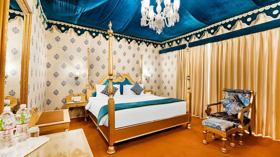 An overview of a tent with a double bed, a chair and a table inside it - Rajasthali Resort & Spa, Jaipur.