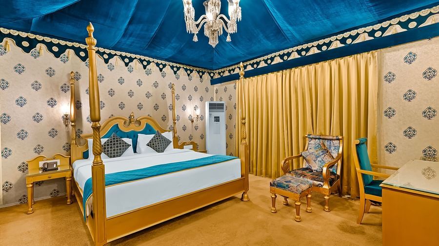 An overview of a tent with a double bed, water cooler and a chair inside - Rajasthali Resort & Spa, Jaipur.