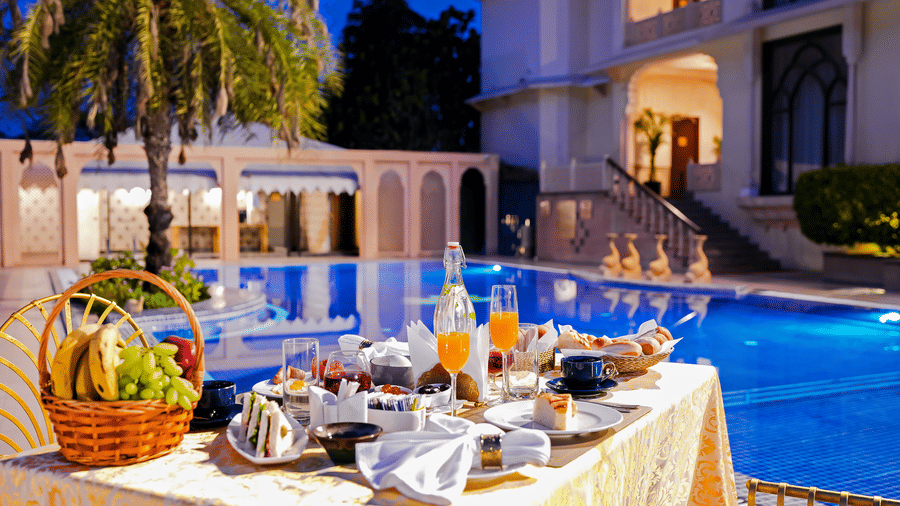A table set up with many items on the table next to the swimming pool - Rajasthali Resort & Spa, Jaipur.