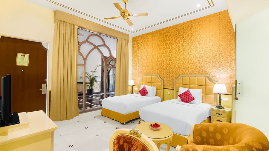An overview of a room with two single beds, a chair and ceiling fan in view - Rajasthali Resort & Spa, Jaipur.
