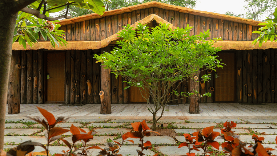 A wooden building with a thatched roof, surrounded by trees and plants, suggests a natural or rustic setting | Casa Room | RD's Nature Retreat, Bangalore