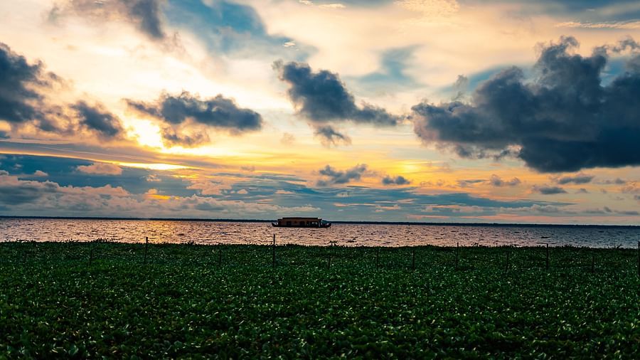 an image of Evening view after the sun set with a houseboat in the water - Rhythm Kumarakom