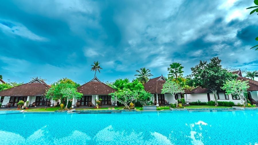 an image of cluster of cottages surrounded by a big swimming pool - Rhythm Kumarakom