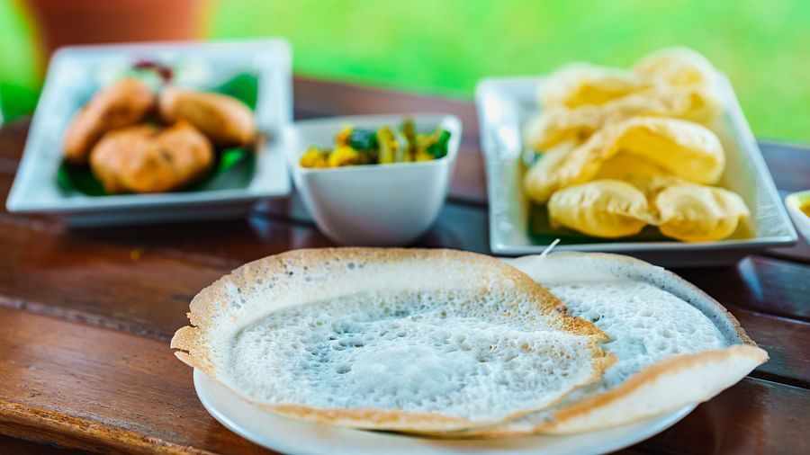 Appam, vada, puri and a side dish on a table at Rhythm Kumarakom