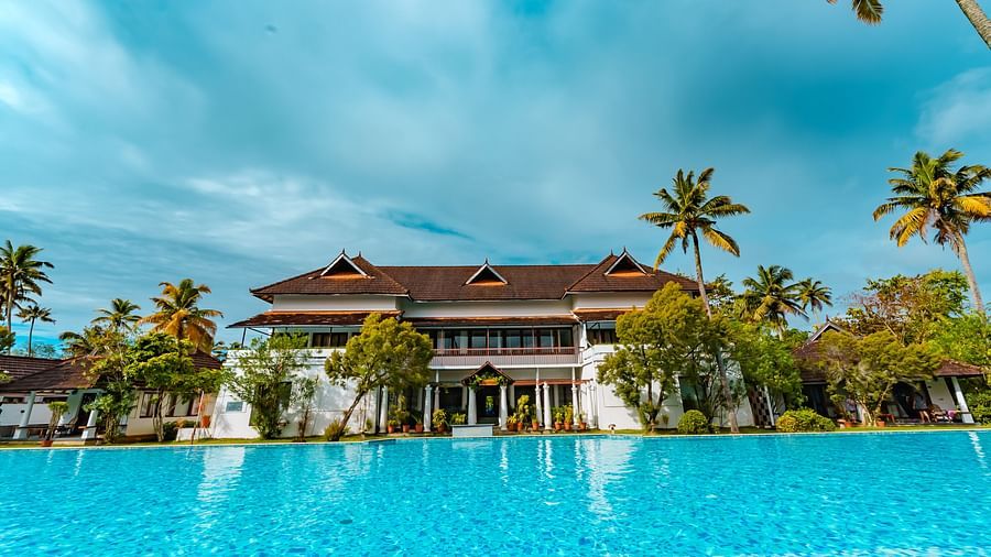 facade image of the spa from with a pool in front of it surrounded coconut trees - Rhythm Kumarakom