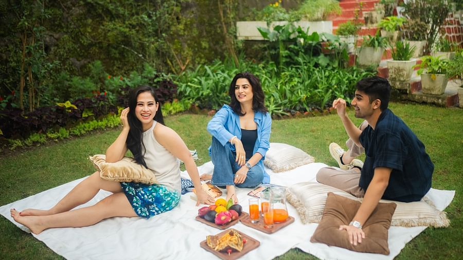 Guests enjoying a picnic with fresh fruits and snacks on a lush green lawn at The Claridges Nabha Residence