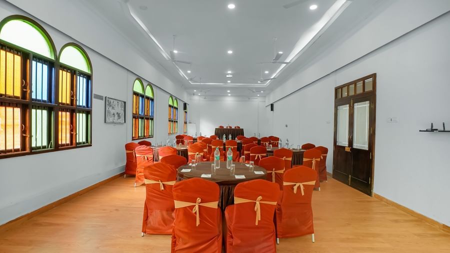 Back view of banquet hall with chairs arranged around a round table at WOW Bungalow, Yercaud.