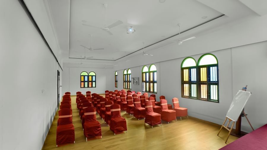 Spacious banquet hall with chairs arranged facing the stage area at WOW Bungalow, Yercaud.