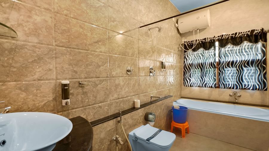 Modern bathroom with a bathtub, western toilet and a wash basin at WOW Bungalow, Yercaud.