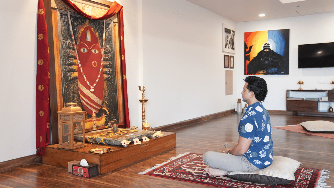 A person praying at a Hindu shrine. It suggests that the resort - Karma Lakelands.