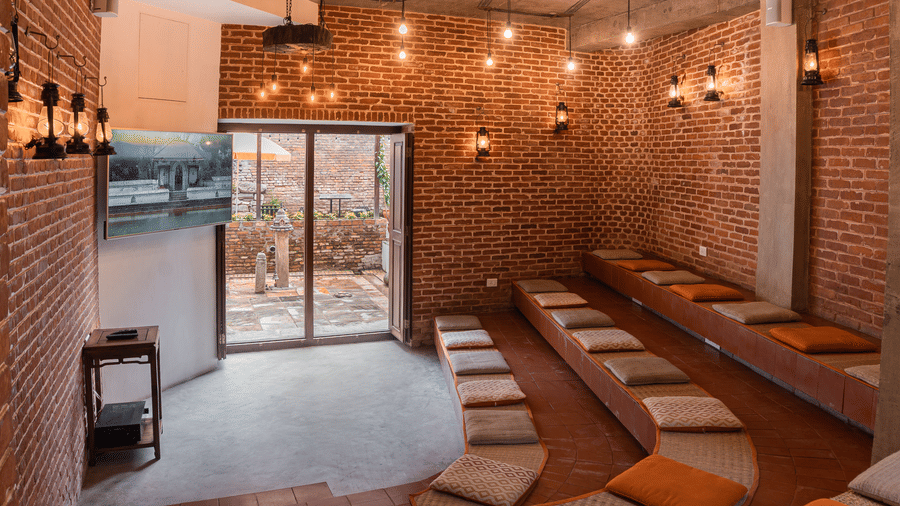 A modern conference room and seminar hall with brick walls and floor seating cushions inside a boutique hotel in Bhaktapur, Nepal.