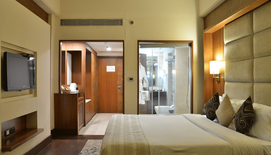 Premium Rooms at The Bristol Hotel Gurgaon, featuring a large bed, pillows, spreads, lamps, and a television.