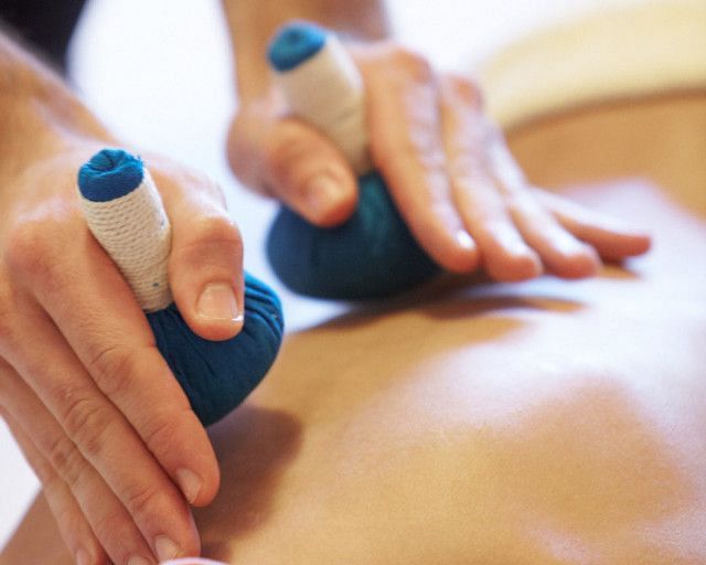 Two hands using blue, rounded tools on a person's back during a massage or therapy session.