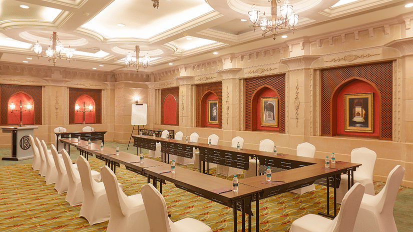 A corner view of Raj Hall at The Residency Tower, Chennai, featuring a board seating arrangement. The space is well-lit with bright lights, and elegant frames adorn the walls, creating a sophisticated ambiance for meetings and events.