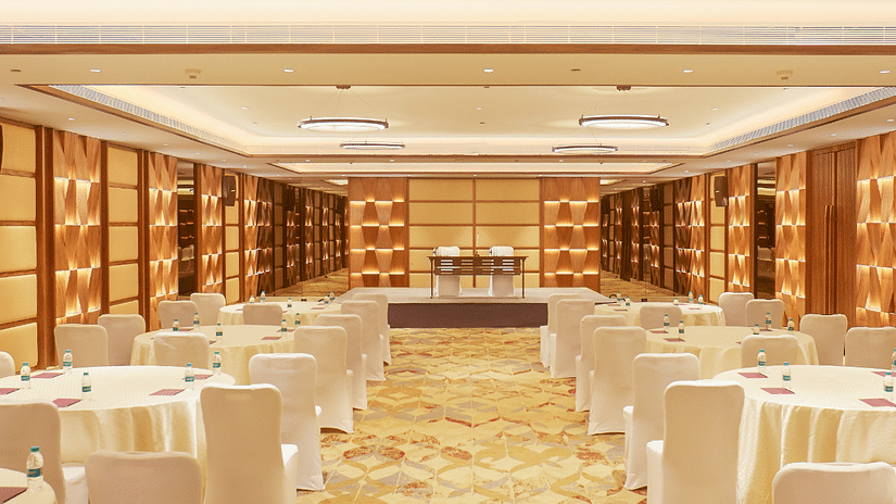 A view from the aisle of Senator Hall at The Residency Tower, Chennai, featuring neatly arranged tables and chairs for seating. The room is designed for events, with elegant decor and ample space, providing a welcoming atmosphere for gatherings and present