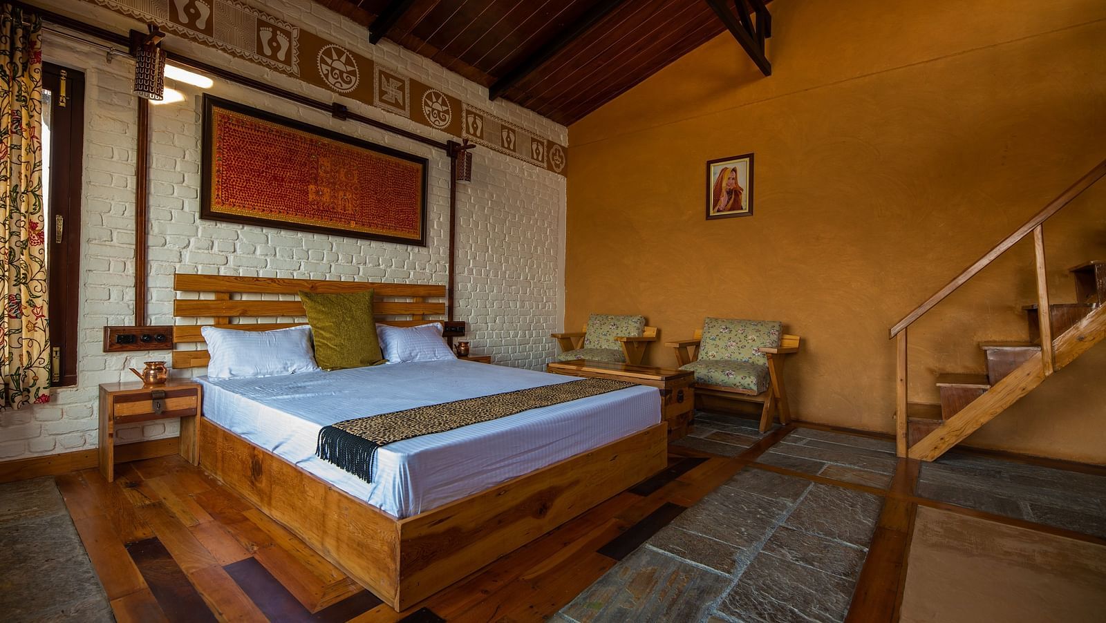 Rustic bedroom with wood bed, patterned textiles, and stairs to right. - Blusalzz Homes The Himalayan Bungalow, Almora