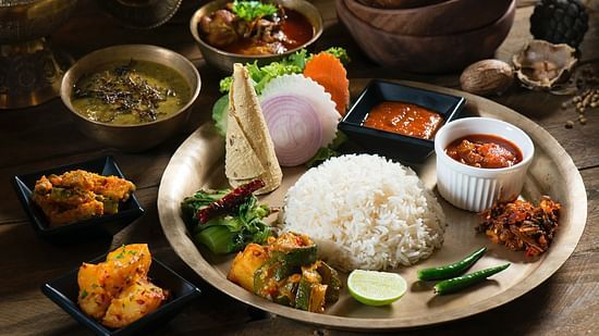 a full course nepali meal with neatly served rice, dal, curries and other vegetable sabzi garnished with green chilly and lemon
