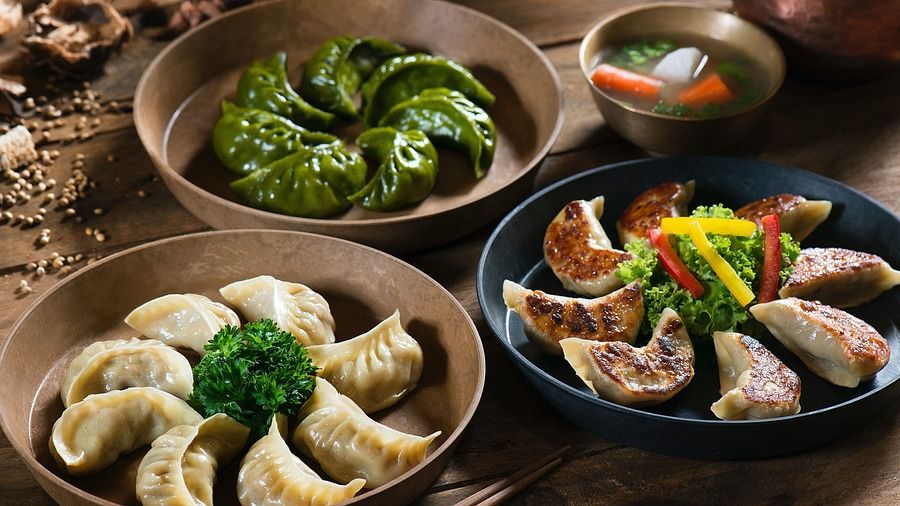 a wooden table containing three plates of dumplings