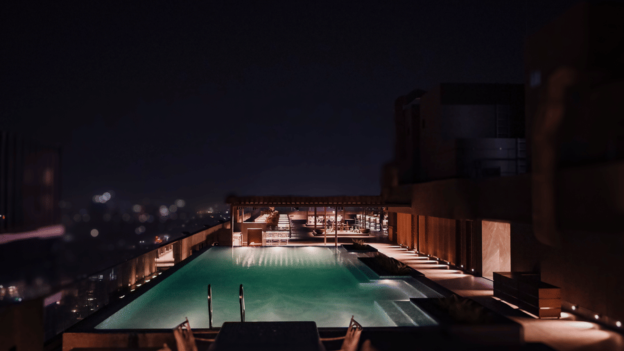 A stunning view of the rooftop swimming pool illuminated at night overlooking the city lights - Praveg's Grand Eulogia, Ahmedabad