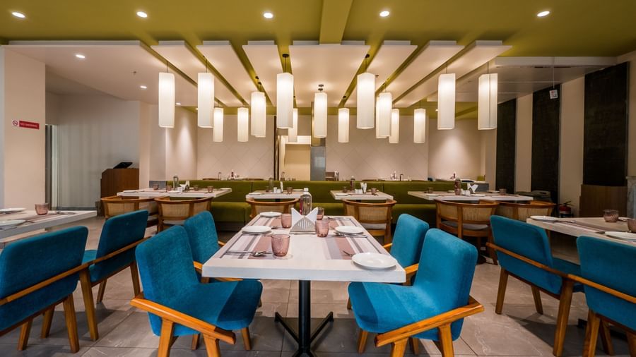 A neatly set dining table with elegant blue chairs and modern decor in a well lit restaurant environment at Shilton Dee Cee.