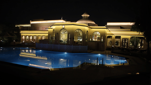 Night view of a luxury property with a beautifully lit swimming pool and grand architecture.