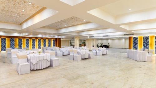Spacious banquet hall with chairs and ceiling lights at Golden Tulip, Udaipur.