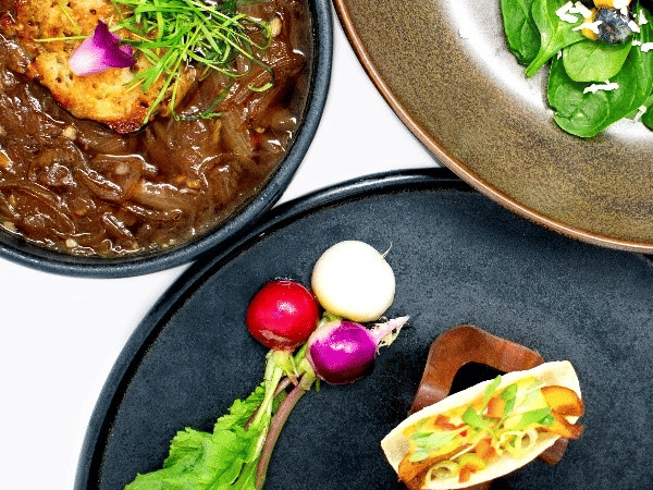 A trio of healthy dishes: a brown stew, a salad with blueberries, and 2 open-faced appetizers at YO1 Longevity & Health Resorts