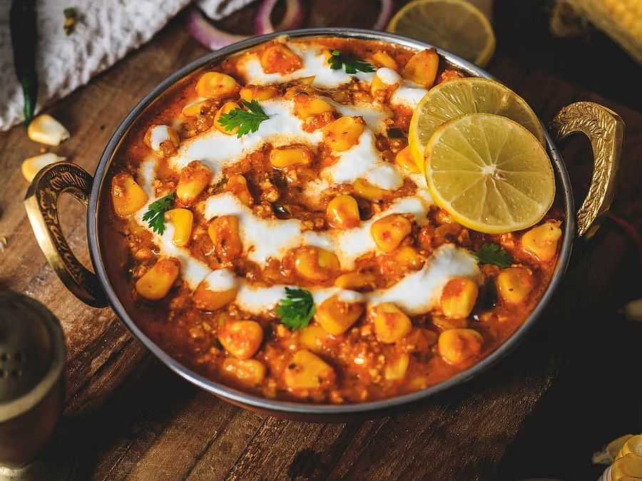 Spicy Indian chaat served in a traditional bowl with garnishes and lemon slices.