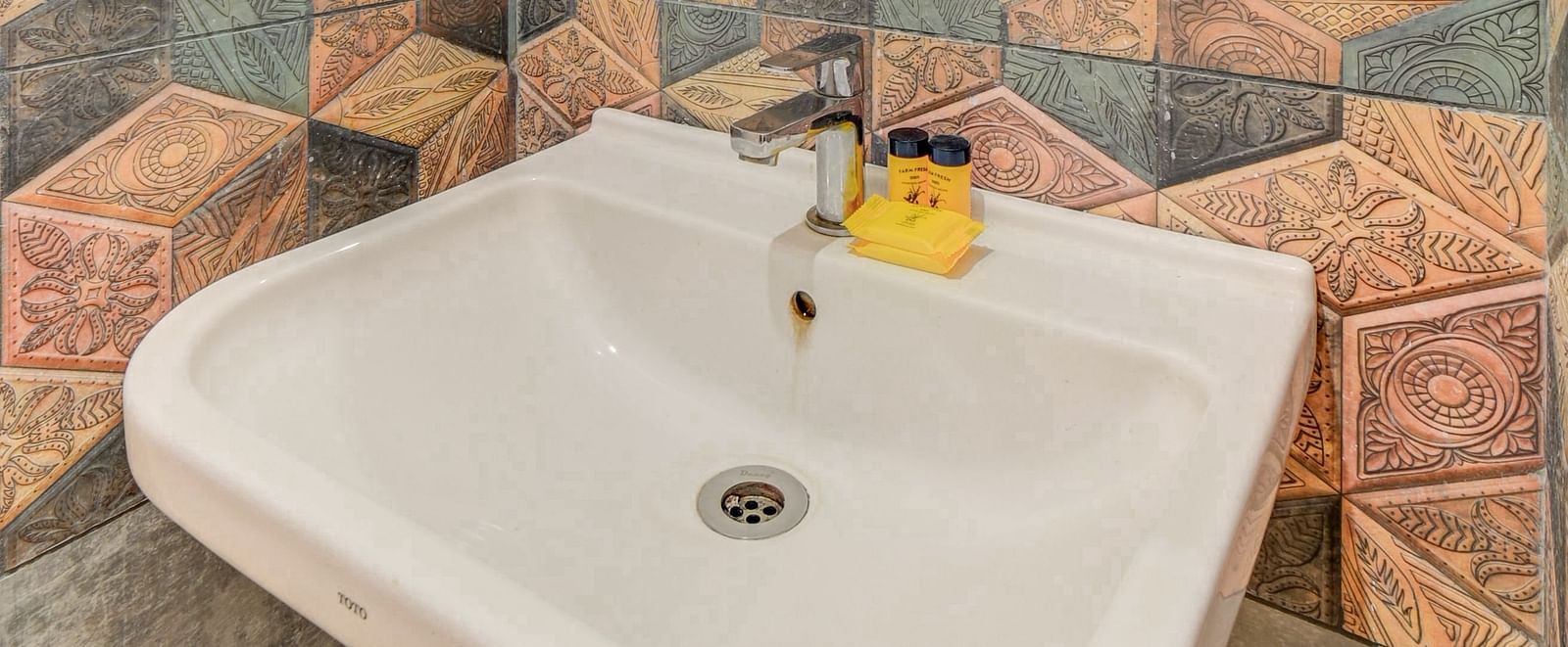A wash basin with a wall-mounted mirror above it at Hari Govinda’s JN Stay, Shakthinagar