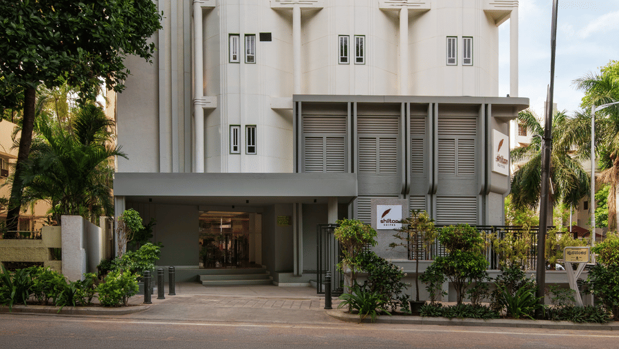 Exterior view of Shilton Suites, Bengaluru, framed by trees and landscaped surroundings.