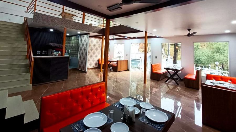 The interiors of the restaurant at DLS Nature Trinket Resort with red couches and tables.