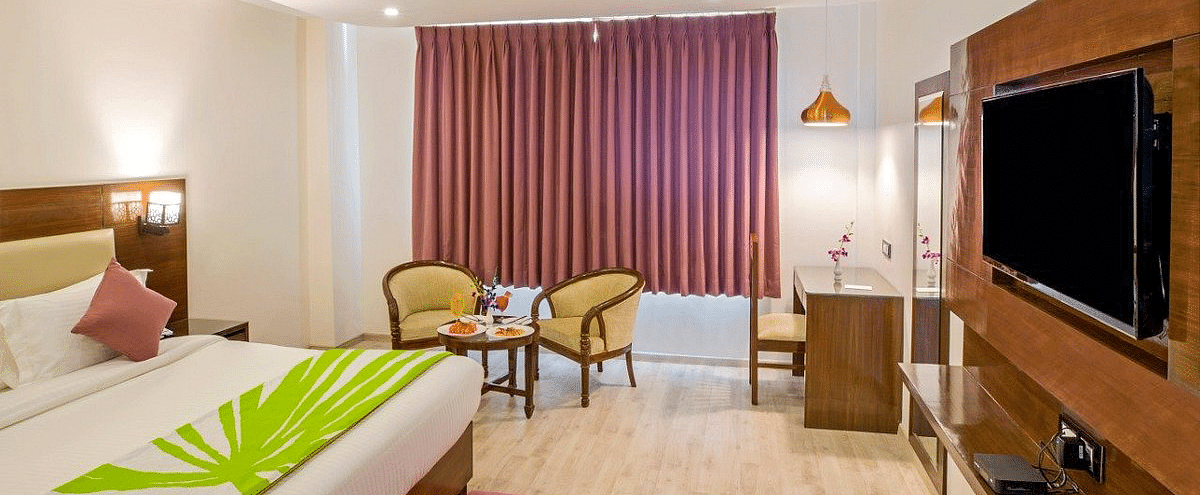 The Premium Room at Regenta Inn DLS with a double bed along with a wall mounted television in front of it.