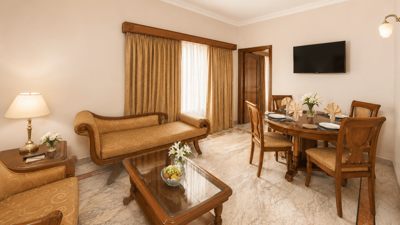 A room at Raj Park, Chennai, with sofas, tables, and a television.