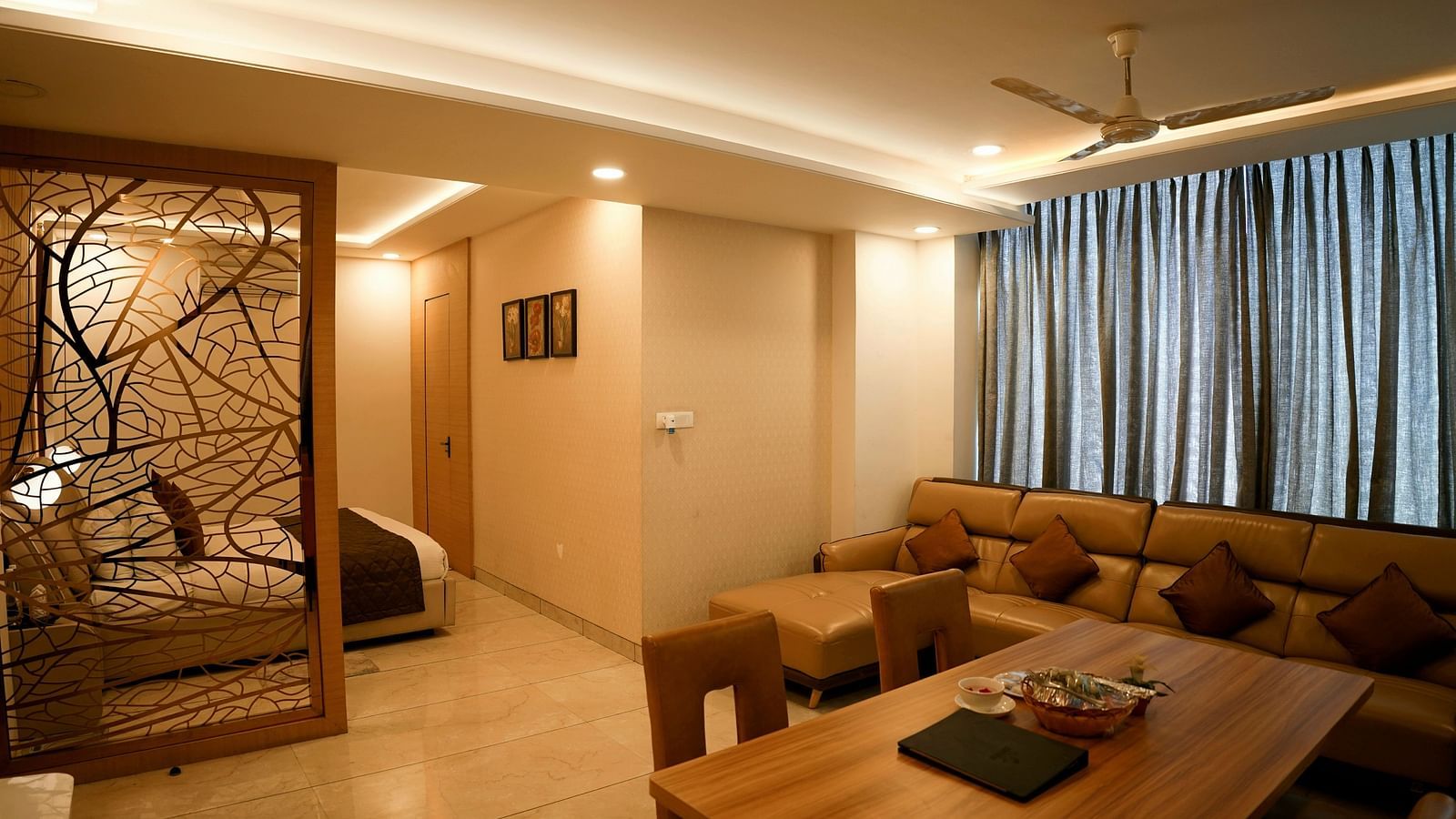 A spacious living room with a sectional sofa and decorative partition leading to another room - TGI Insignia, Bhopal